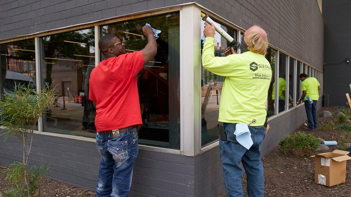 Workers replace windows smashed in May at a business in downtown Omaha, Neb., on Wednesday, one day after a grand jury decided to charge a white business owner who fatally shot Black James Scurlock during civil unrest in downtown Omaha this spring with manslaughter and other charges. (AP Photo/Nati Harnik)