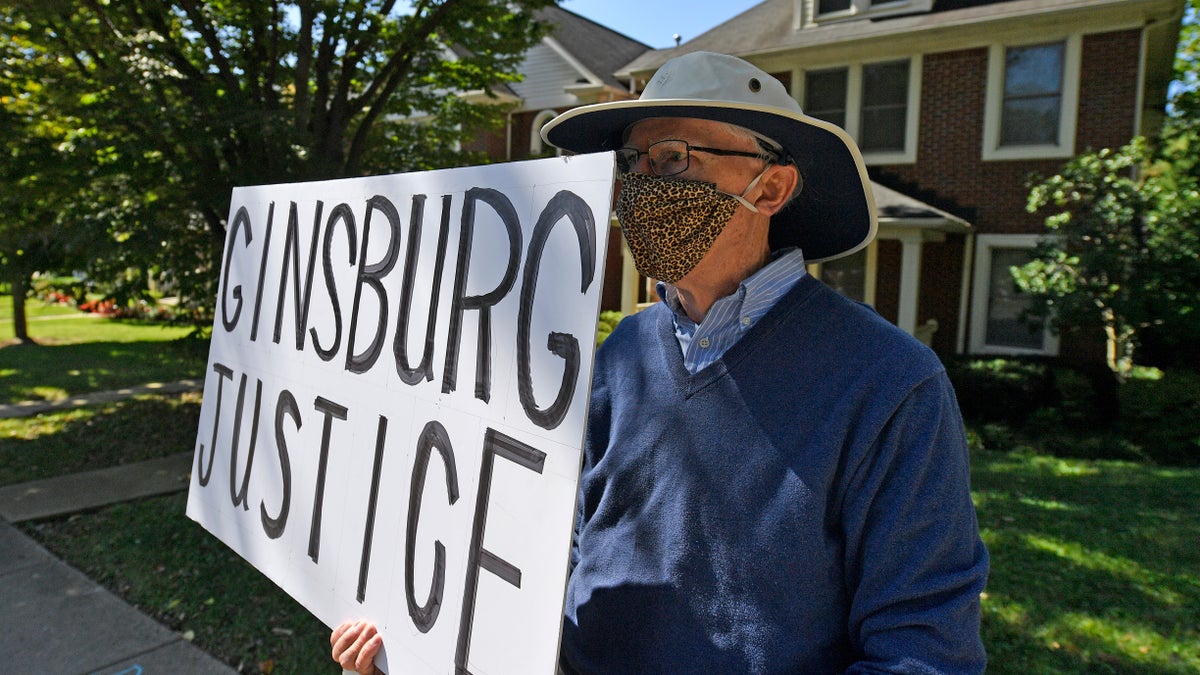 A protester stands outside the house of Senate Majority Leader Mitch McConnell, R-Ky., in Louisville, Ky., Saturday, Sept. 19, 2020. McConnell vowed on Friday night, hours after the death of Supreme Court Justice Ruth Bader Ginsburg to call a vote for whomever President Donald Trump nominated as her replacement. (AP Photo/Timothy D. Easley)