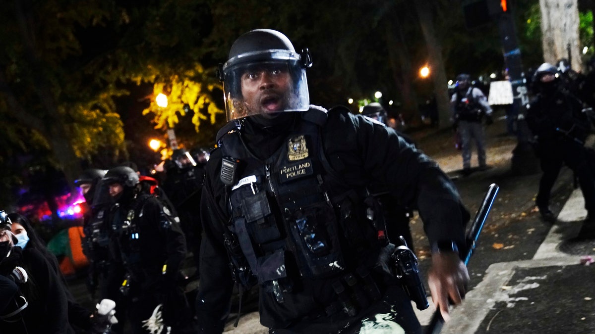 A Portland police officer pushes back protesters, Saturday, Sept. 26, 2020, in Portland. (AP Photo/John Locher)