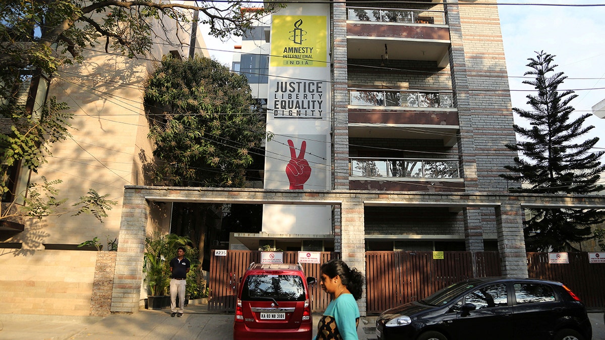 FILE - In this Tuesday, Feb. 5, 2019, file photo, a woman walks past the Amnesty International India headquarters in Bangalore, India. The Human rights watchdog said on Tuesday, Sept. 29, 2020, that it was halting its operation in India, citing reprisals from the government and the freezing of its bank accounts. Its announcement comes at a time amid growing concerns over the state of free speech in India where critics accuse Prime Minister Narendra Modi and his Hindu nationalist government of increasingly brandishing laws to silence human rights activists, intellectuals, filmmakers, students and journalists. (AP Photo/Aijaz Rahi, File)