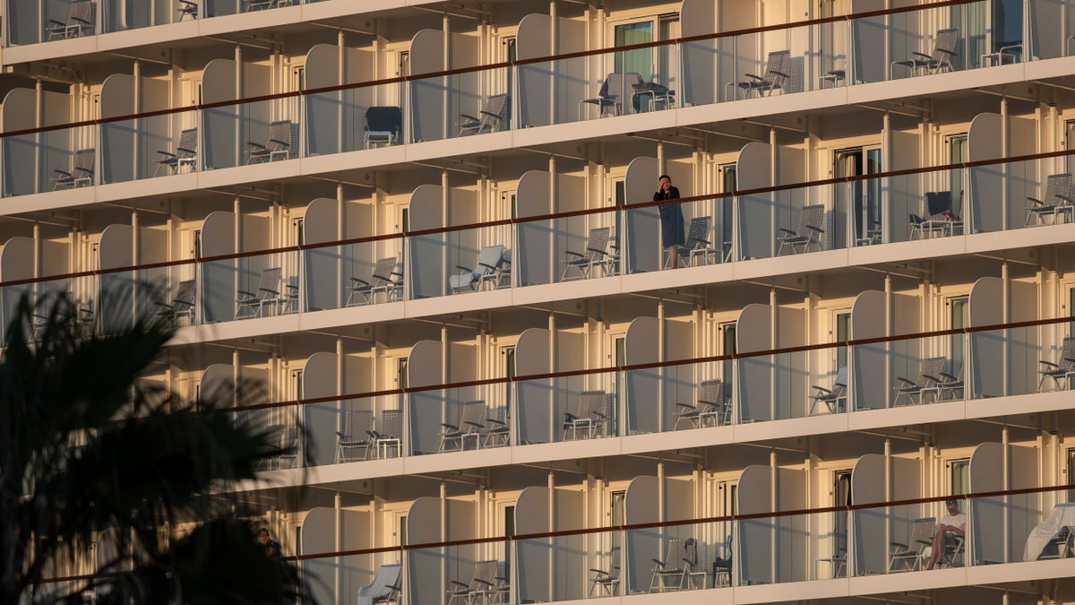 A passenger of the Mein Schiff 6 cruise ship stands outside her cabin as the ship is docked at Piraeus port, near Athens on Tuesday, Sept. 29. (AP Photo/Petros Giannakouris)