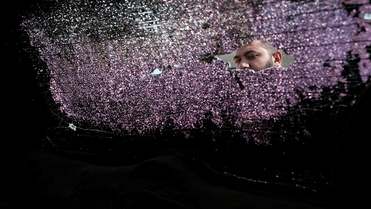 A man looks through a broken window of a car damaged by shelling in Stepanakert, the self-proclaimed Republic of Nagorno-Karabakh, Azerbaijan, Tuesday, Sept. 29, 2020. Armenian and Azerbaijani forces accused each other of attacks on their territory Tuesday, as fighting over the separatist region of Nagorno-Karabakh continued for a third straight day following the reigniting of a decades-old conflict. (Areg Balayan/PAN Photo via AP)