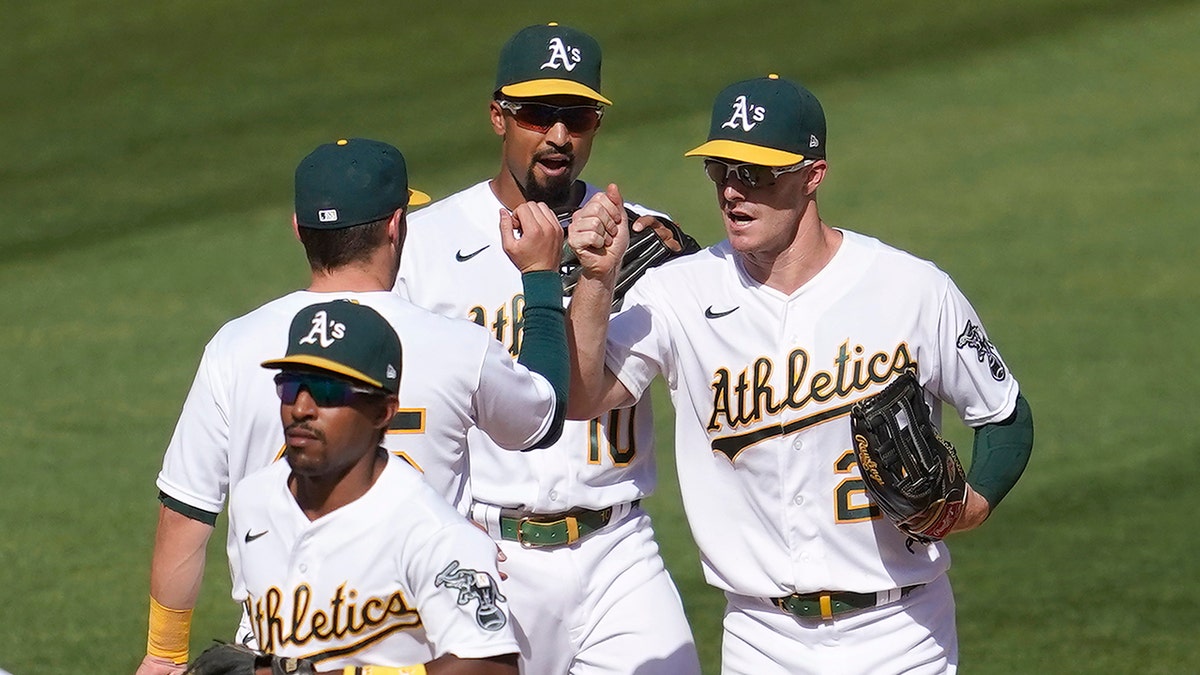 Oakland Athletics' Nate Orf, rear facing left, celebrates with Marcus Semien and Mark Canha after the Athletics defeated the Seattle Mariners in a baseball game in Oakland, Calif., Sunday, Sept. 27, 2020. Also pictured is Tony Kemp, foreground. (AP Photo/Jeff Chiu)