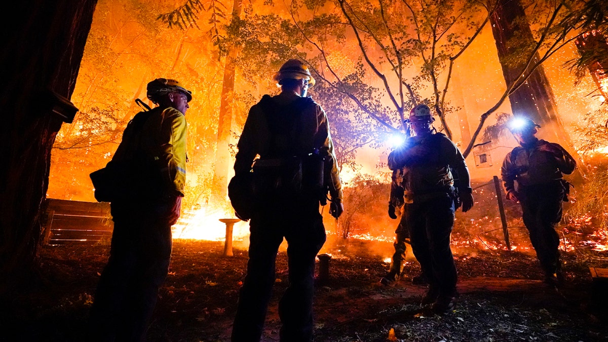 Firefighters make a stand in the backyard of a home in front of the advancing CZU August Lightning Complex Fire Friday, Aug. 21, 2020, in Boulder Creek, Calif.