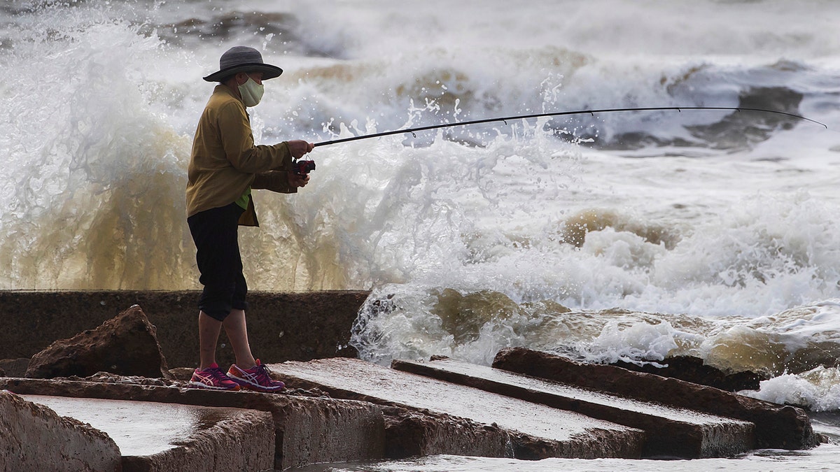 Waves crash as Houston resident Tinh Pham fishes from the rocks at Diamond Beach on the west end of the Galveston Seawall in Galveston, Texas on Saturday, Sept. 19, 2020.
