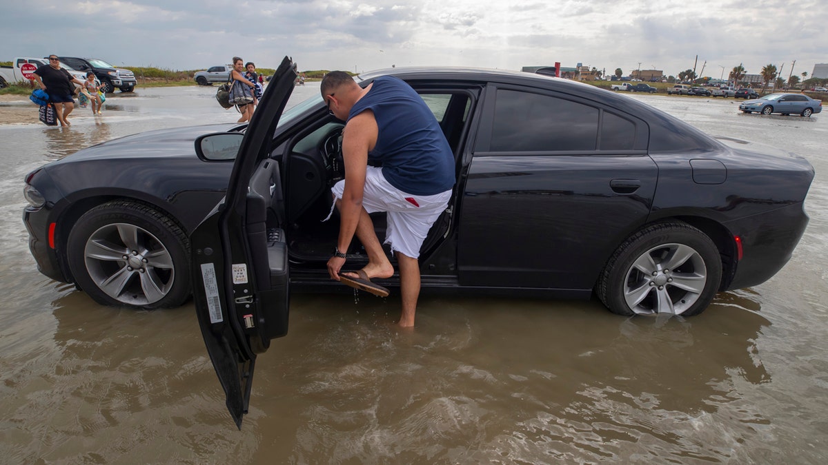 Houston resident Lupe Don removes his flip-flops while moving his car from the flooding Stewart Beach parking lot in Galveston, Texas on Saturday, Sept. 19, 2020.