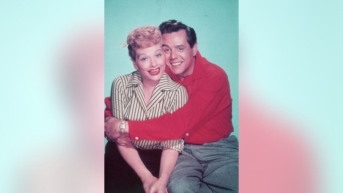 circa 1955:  Studio portrait of American actor and comedian Lucille Ball receiving a hug from her husband, Cuban-born bandleader and singer Desi Arnaz, against a green backdrop.  