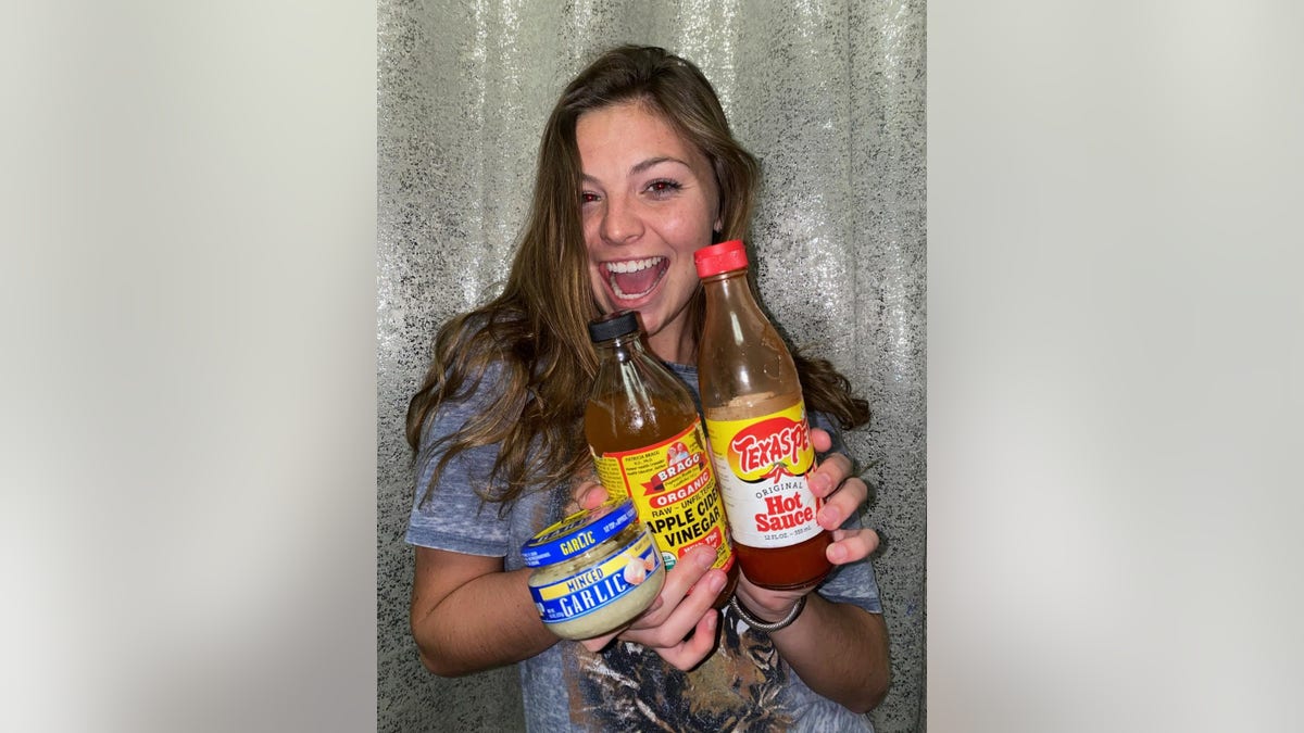 TikTok user Cammie Cooke poses with garlic, apple cider vinegar and hot sauce for her COVID food review. (Cammie Cooke)