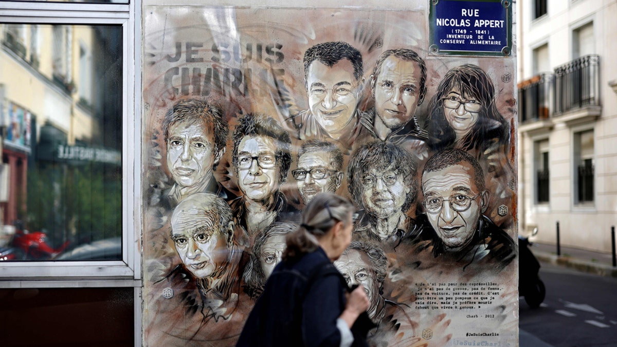 A woman walks past a painting by French street artist and painter Christian Guemy, known as C215, in tribute to members of Charlie Hebdo newspaper who were killed by jihadist gunmen in January 2015. (THOMAS COEX/AFP via Getty Images)