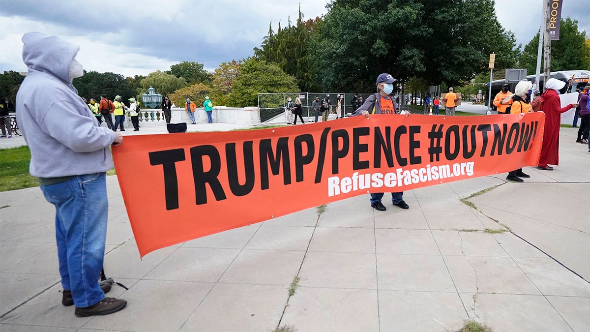 Protesters hold up a sign near the debate hall, Tuesday, Sept. 29, 2020, in Cleveland. The first presidential debate between Republican candidate President Donald Trump and Democratic candidate and former Vice President Joe Biden is being held in Cleveland Tuesday. (AP Photo/Tony Dejak)