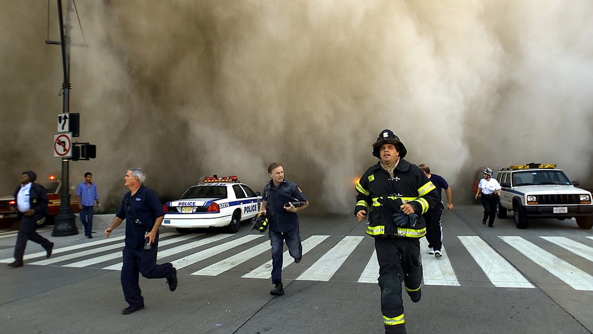 Policemen and firemen run away from the huge dust cloud caused as the World Trade Center's Tower One collapses after terrorists crashed two hijacked planes into the twin towers, September 11, 2001 in New York City. (Photo by Jose Jimenez/Primera Hora/Getty Images)