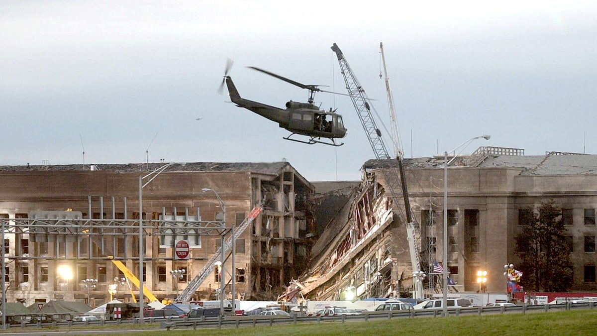 A military helicopter flies in front of the Pentagon September 14, 2001 in Arlington, Virginia at the impact site where a hijacked airliner crashed into the building. (Photo by Stephen J. Boitano/Getty Images)