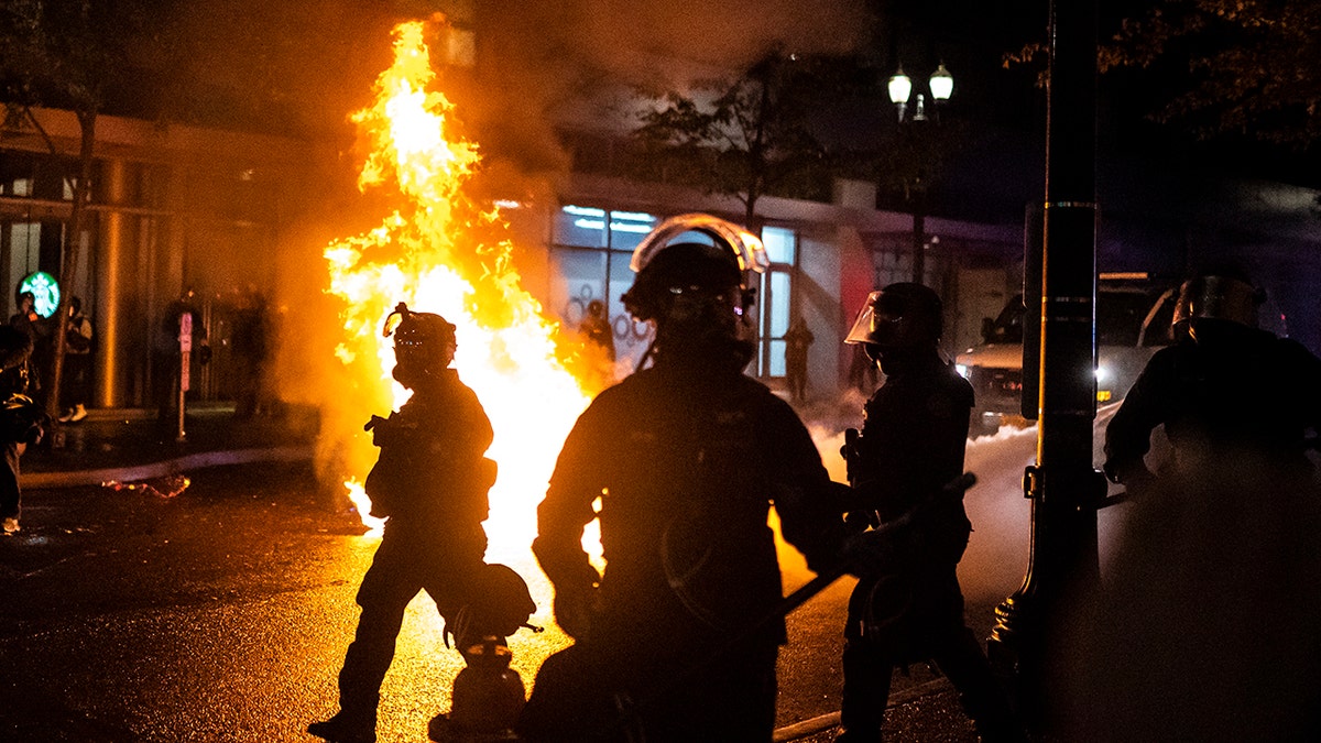 Portland police walk past a fire started by a Molotov cocktail thrown at police on Sept. 23, 2020 in Portland. (Photo by Nathan Howard/Getty Images)