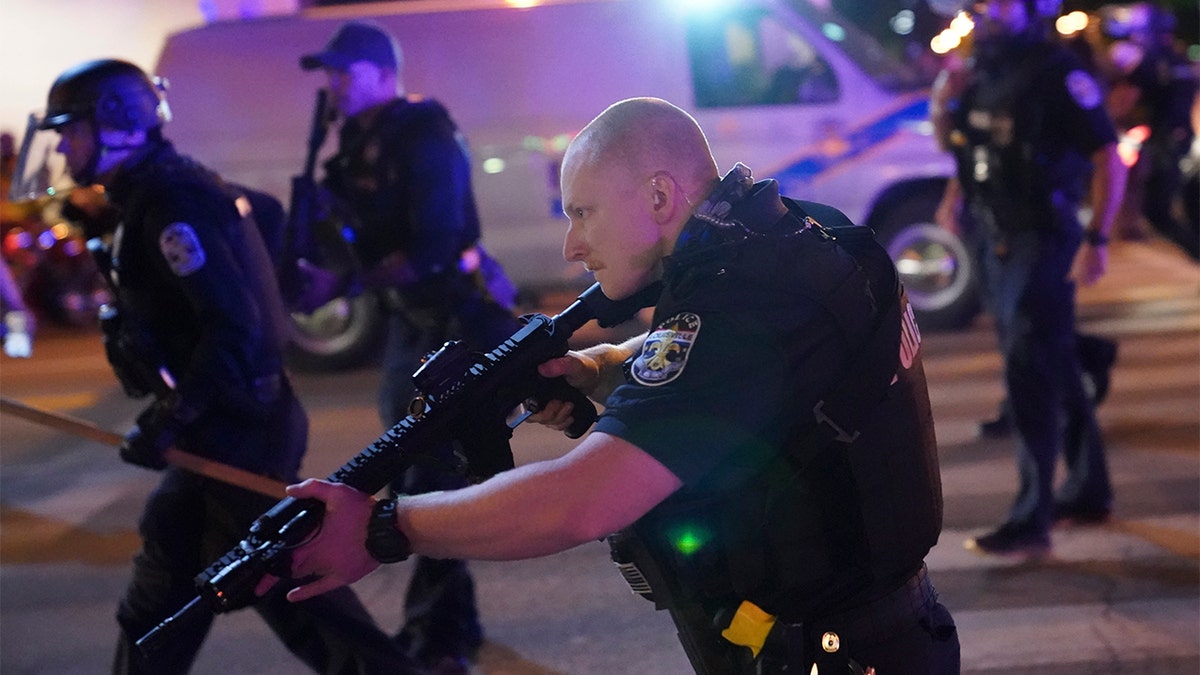 Police move after a Louisville Police officer was shot, Wednesday, Sept. 23, 2020, in Louisville, Ky. (AP Photo/John Minchillo)