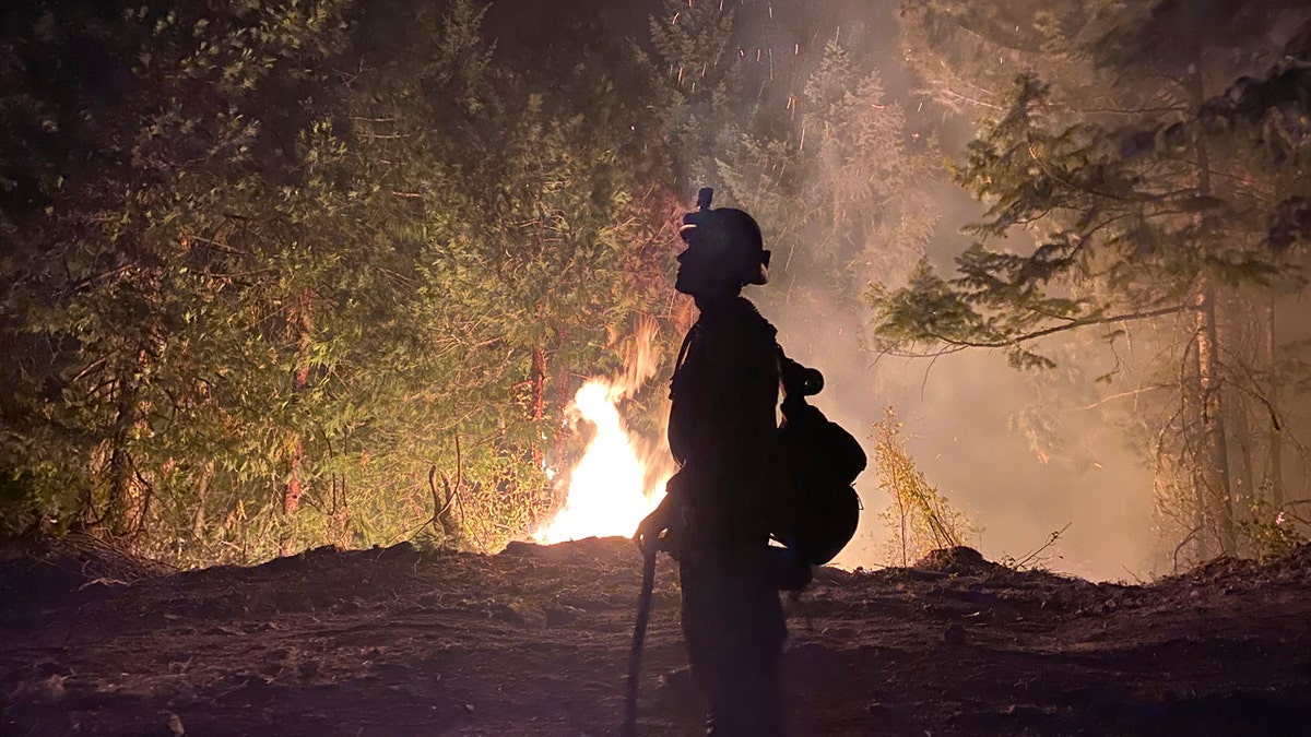 This photo provided by the Unified Fire Authority shows a Utah fire crew member on the scene working to protect the town of Butte Falls in southern Oregon.