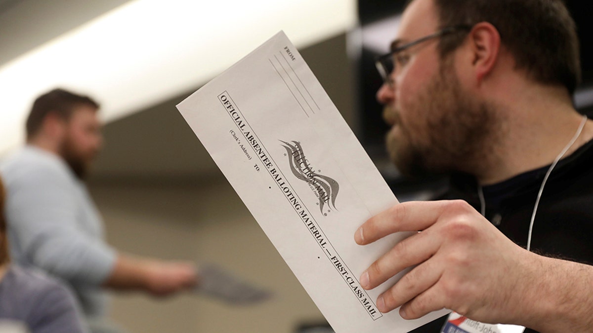 Election volunteer Tyler Jentoft-Johnson holds an absentee ballot as they're counted at the City Hall during the presidential primary election held amid the coronavirus disease (COVID-19) outbreak in Beloit, Wisconsin, U.S. April 7, 2020. REUTERS/Daniel Acker