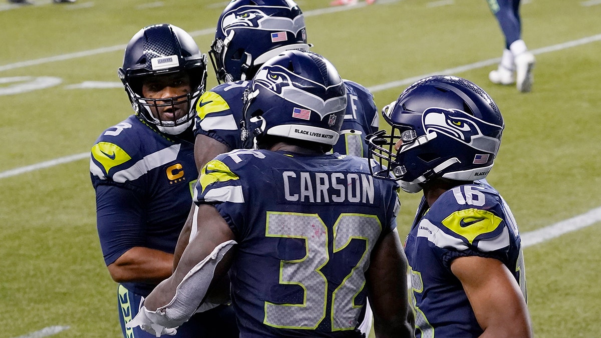 Seattle Seahawks running back Chris Carson (32) is greeted by quarterback Russell Wilson, left, after Carson caught a pass from Wilson for a touchdown against the New England Patriots during the second half of an NFL football game, Sunday, Sept. 20, 2020, in Seattle. (AP Photo/Elaine Thompson)