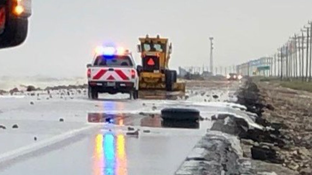 Storm surge flooding can be seen causing problems on Texas State Highway 87 along the Texas Gulf Coast, with debris on the roadway.