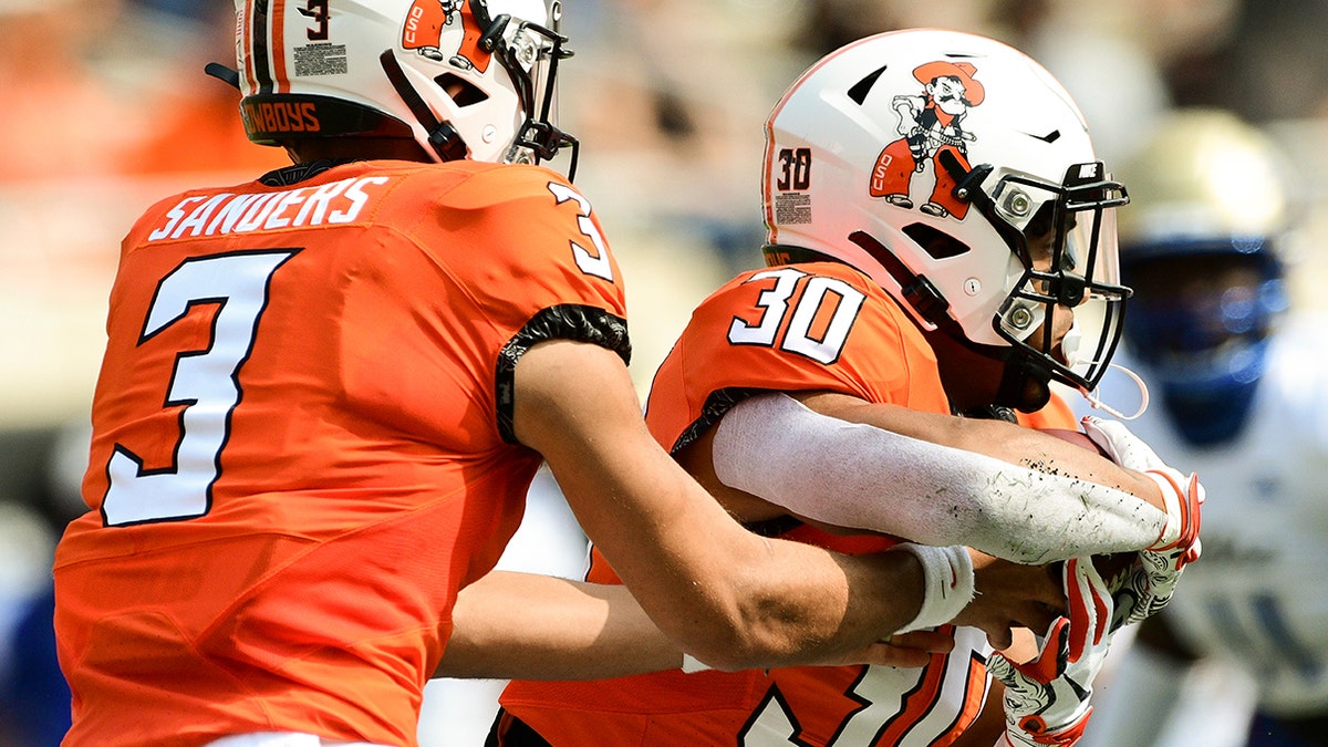 Oklahoma State quarterback Spencer Sanders (3) hands the ball off to running back Chuba Hubbard (30) during the first half of an NCAA college football game against Tulsa, Saturday, Sept. 19, 2020, in Stillwater, Okla. (AP Photo/Brody Schmidt)