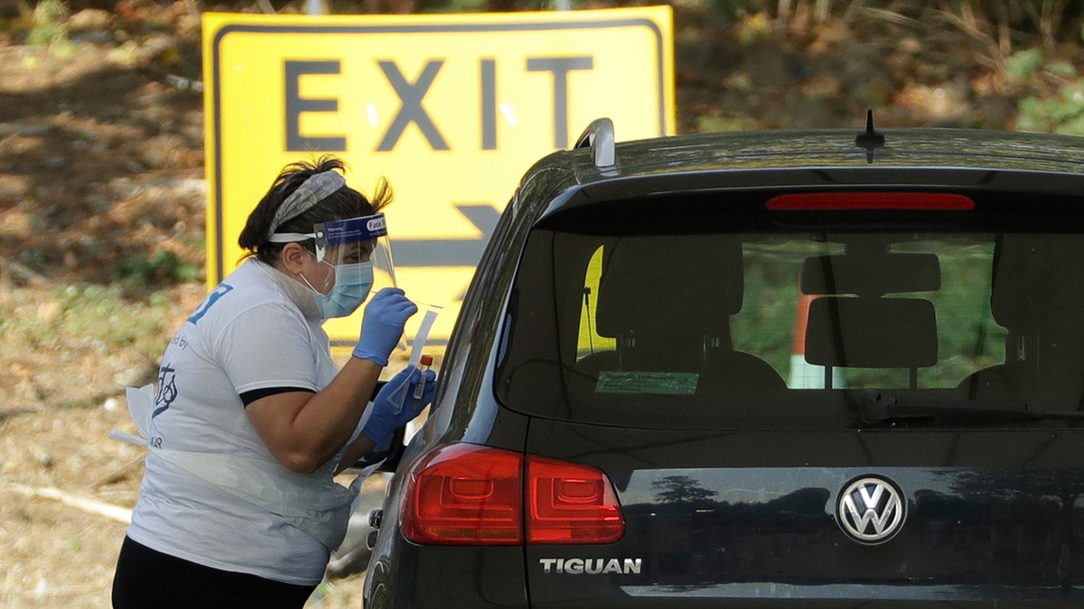 A person is tested for COVID-19 at a drive-through testing centre in a car park at Chessington World of Adventures, in Chessington, Greater London, Saturday, Sept. 19, 2020.