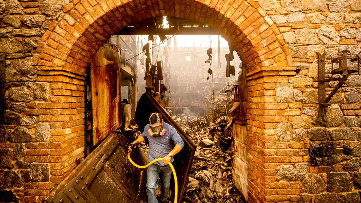 Cellar worker Jose Juan Perez extinguishes hotspots at Castello di Amorosa, Monday, Sept. 28, 2020, in Calistoga, Calif., which was damaged in the Glass Fire.