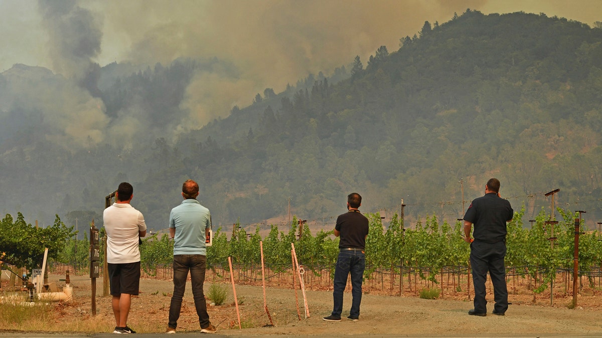 People gather to watch as the Glass Fire burns above in the hills of Calistoga, Calif., on Monday, Sept. 28, 2020.
