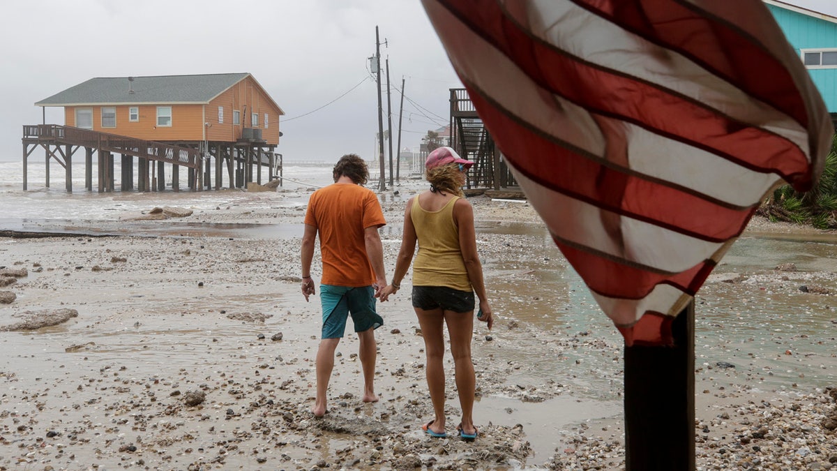 Adam Maubach, left, and Jo Dove look at the erosion caused by Tropical Storm Beta on Monday, Sept. 21, 2020, in Surfside, Texas.