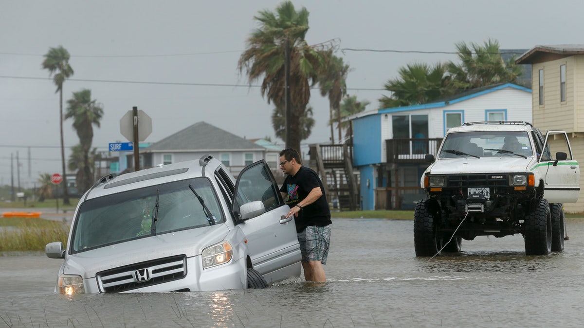 Jeff Williams gets back in his vehicle to try to get it out of the flooded road Monday, Sept. 21, 2020, in Surfside, Texas.