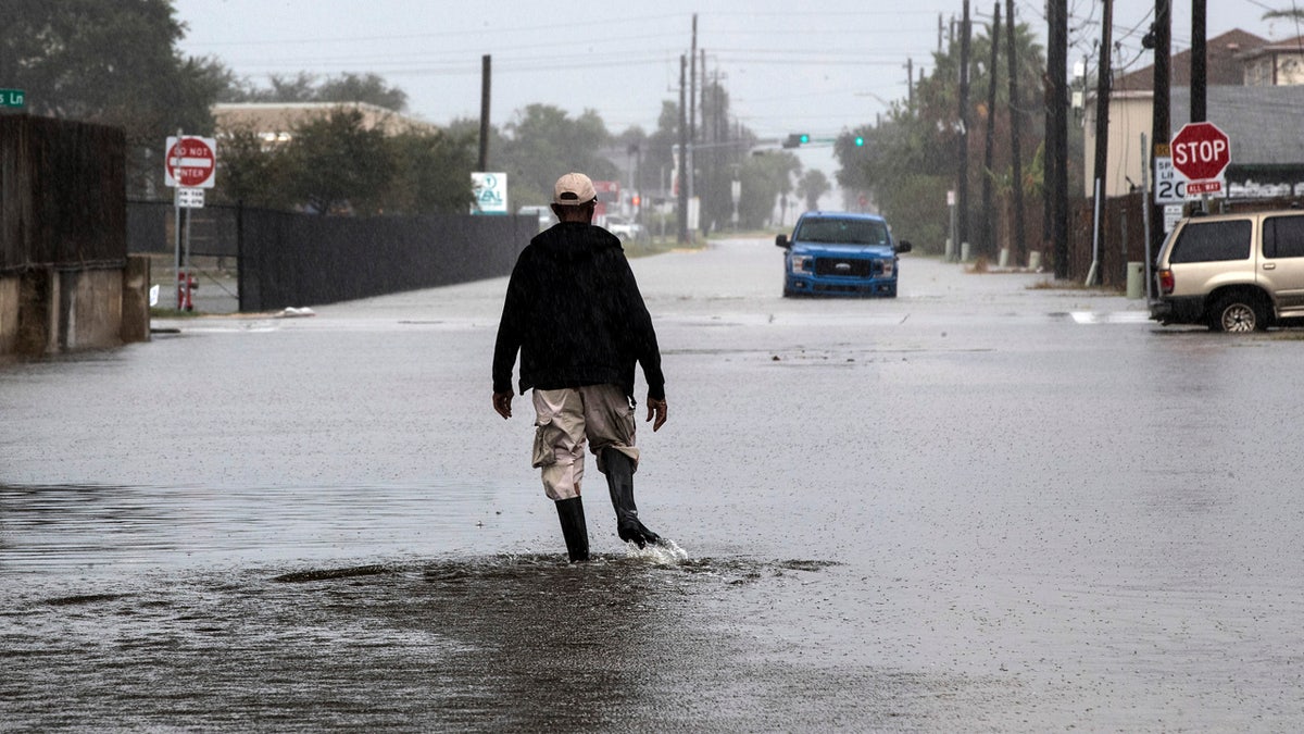 A man walks through a street flooded by Tropical Storm Beta Monday, Sept. 21, 2020, in Galveston, Texas.