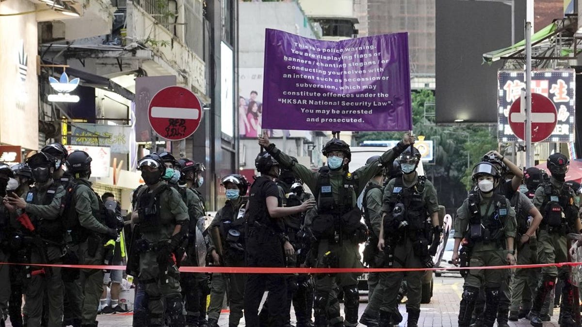 Police officers raise a warning banner at a downtown street in Hong Kong Sunday, Sept. 6, 2020. About 30 people were arrested Sunday at protests against the government's decision to postpone elections for Hong Kong's legislature, police and a news report said. (AP Photo/Vincent Yu)