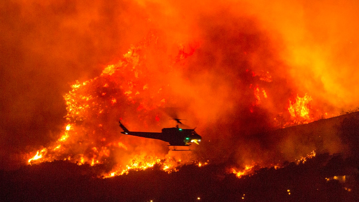 In this Saturday, Sept. 5, 2020, file photo, a helicopter prepares to drop water at a wildfire in Yucaipa, Calif.