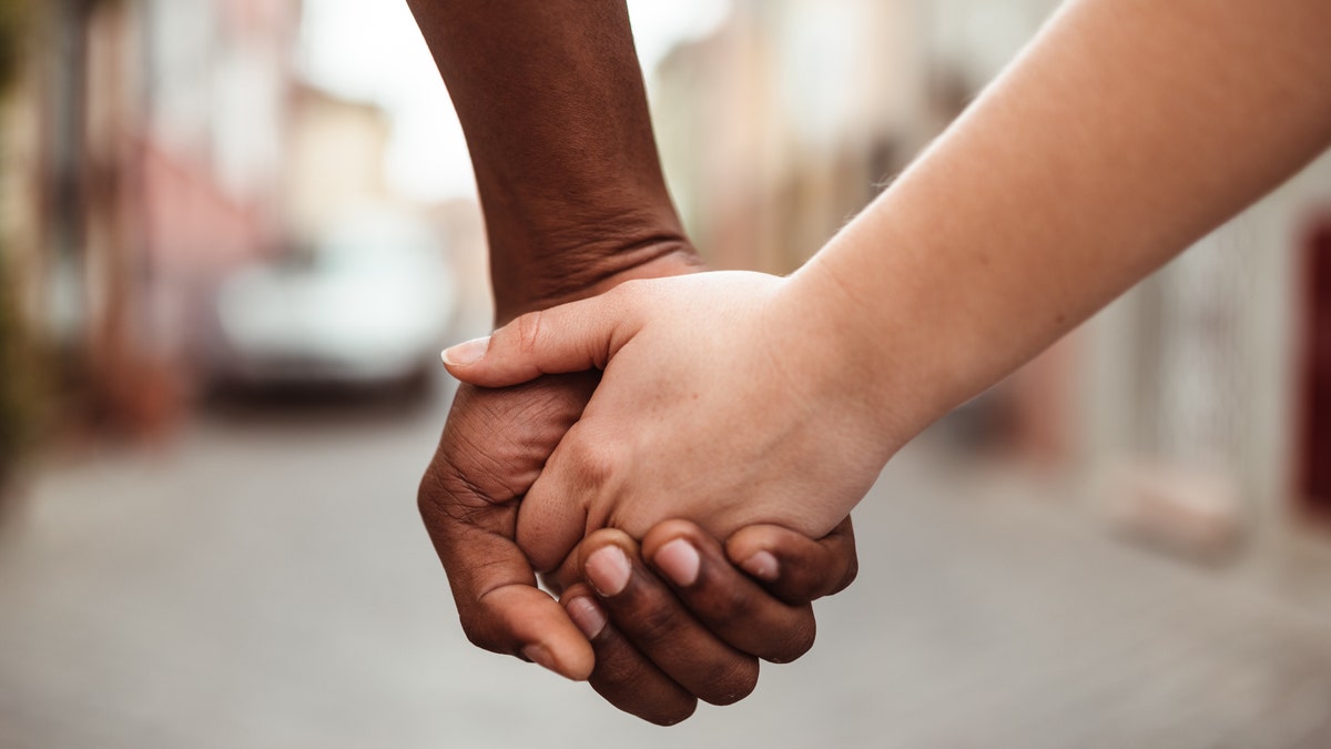 Couple holds hands while walking down the street