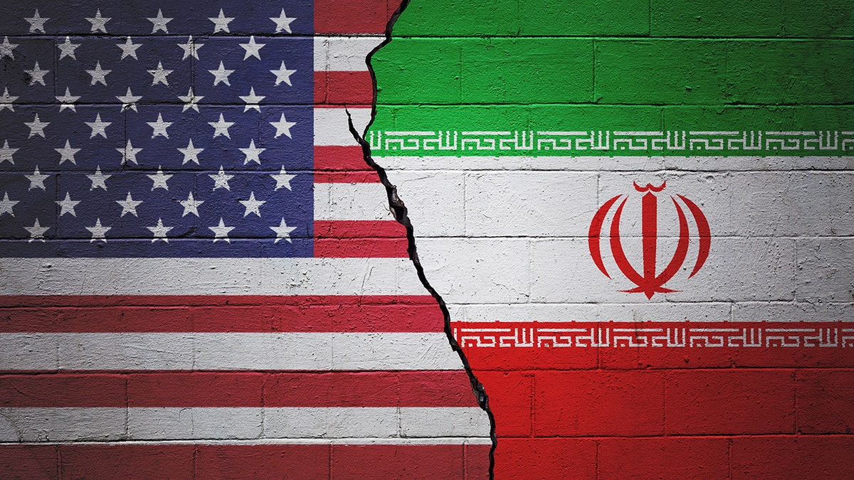 A cracked brick wall painted with an American flag on the left and an Iranian flag on the right.