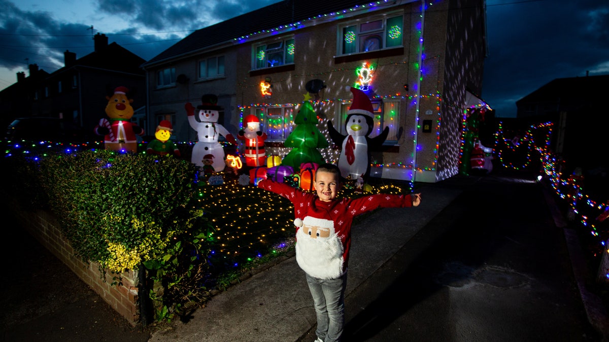Theo Gabe, 5, outside of his home in Wales, which mom Caroline has decorated with 3,000 Christmas lights, sparkling snow and oversized, inflatable yuletide characters.