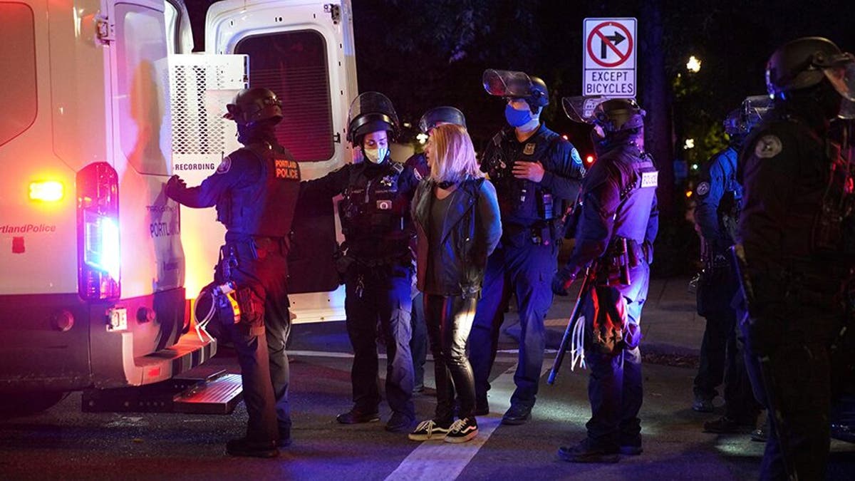 A female protester is loaded into a van after being arrested while rallying at the Mark O. Hatfield United States Courthouse on Saturday, Sept. 26, 2020, in Portland, Ore. (Associated Press)