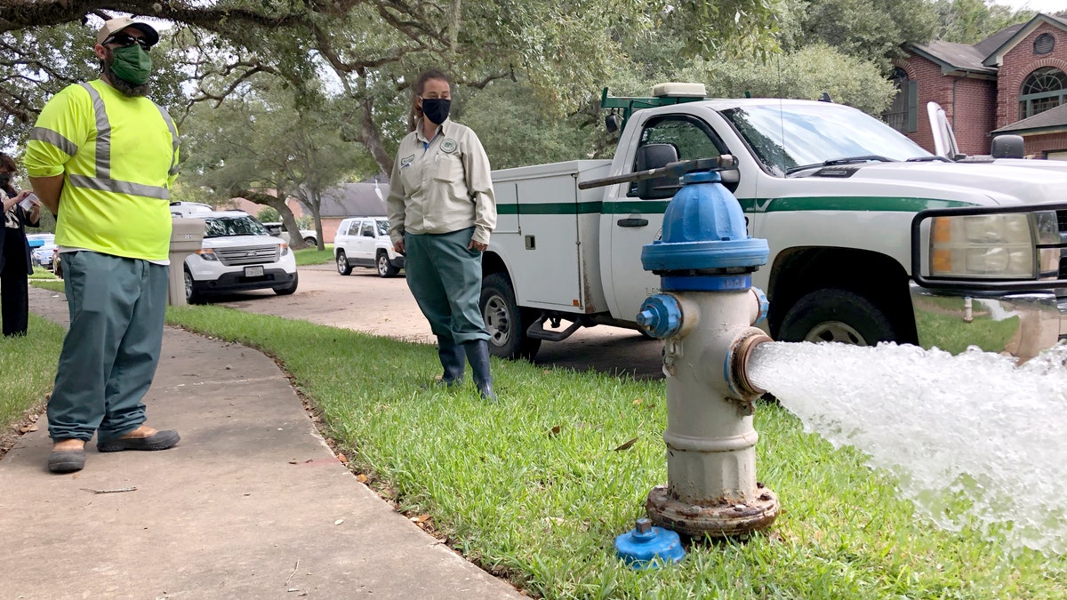 City workers Kristina Watson, right, and Lennie Miner, a maintenance foreman monitor Monday, Sept. 28, 2020, test water flowing out of a hydrant in Lake Jackson, Texas.