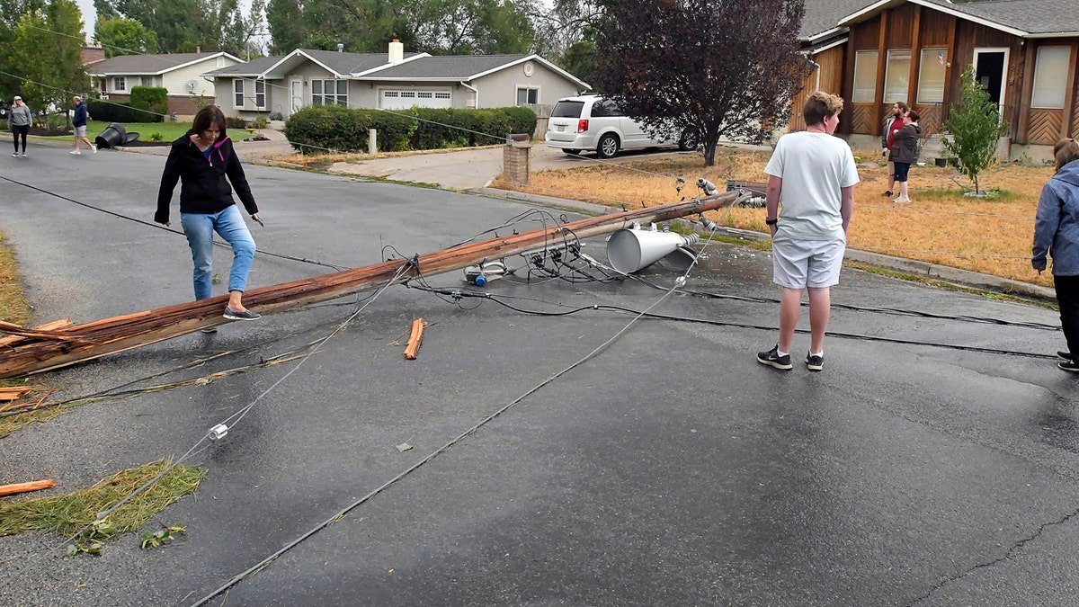Residents look at a downed power pole that was blown over in high winds on Tuesday, Sept. 8, 2020, in Hyrum, Utah.