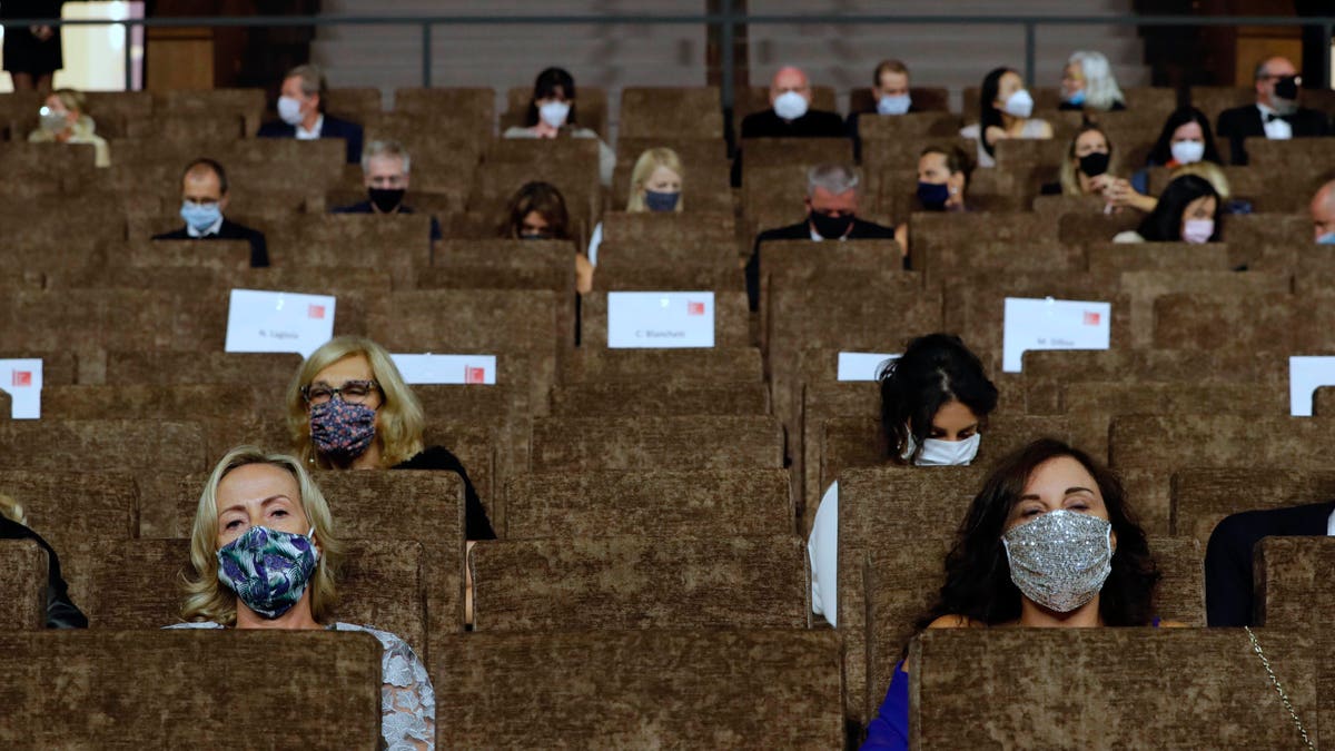 Guests wear face masks as they wait for the start of the opening ceremony of the 77th edition of the Venice Film Festival at the Venice Lido, Italy, Wednesday, Sep. 2, 2020. The Venice Film Festival will go from Sept. 2 through Sept. 12. Italy was among the countries hardest hit by the coronavirus pandemic, and the festival will serve as a celebration of its re-opening and a sign that the film world, largely on pause since March, is coming back as well.