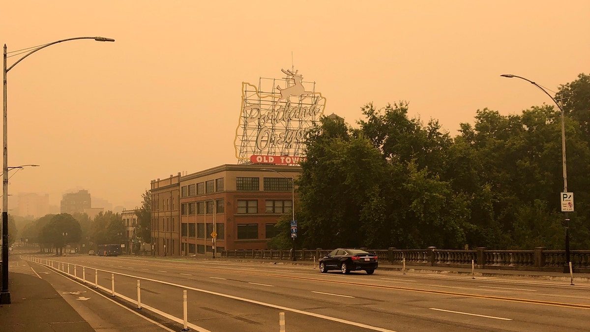 The Portland Oregon Old Town sign is seen under heavy smoke from the wildfires creating an orange glow over Portland, Ore., Saturday, Sept. 12, 2020.