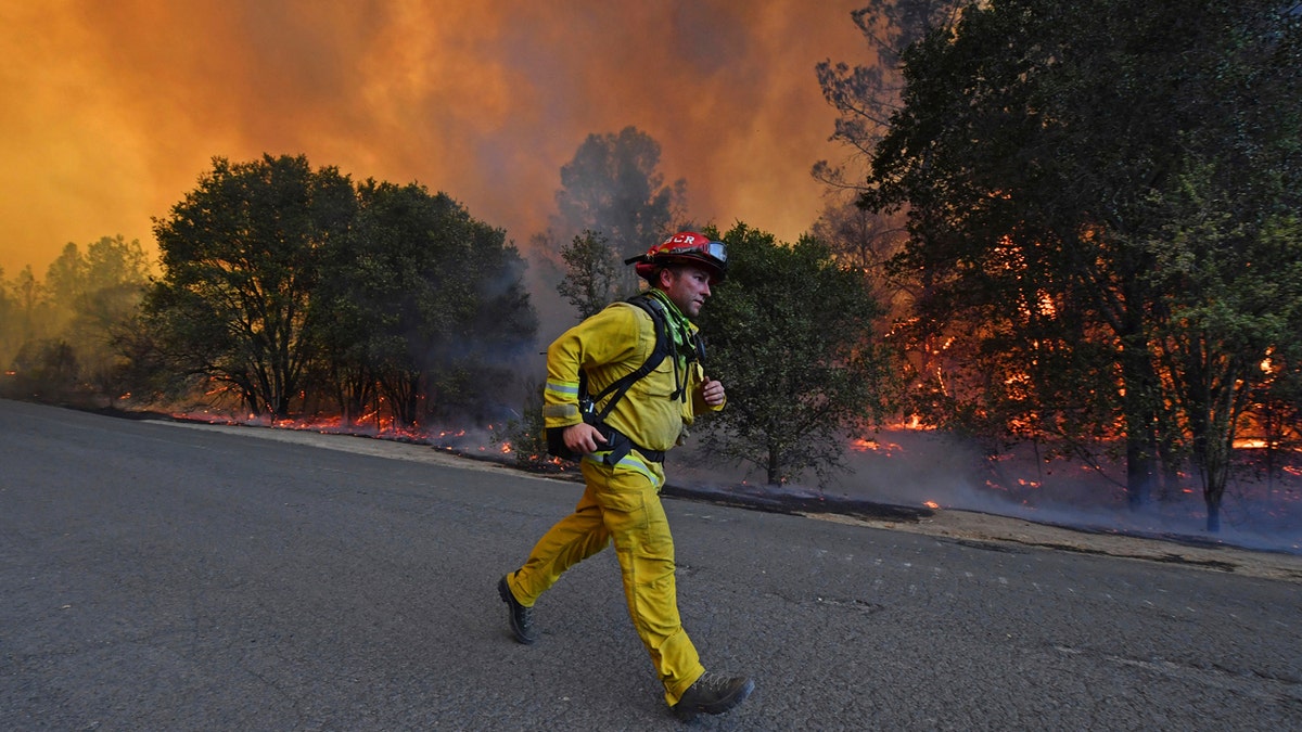 A firefighter runs to his firetruck while protecting a home along Crystal Springs Road while battling the Glass Fire in St. Helena, Calif., on Sunday, Sept. 27, 2020.