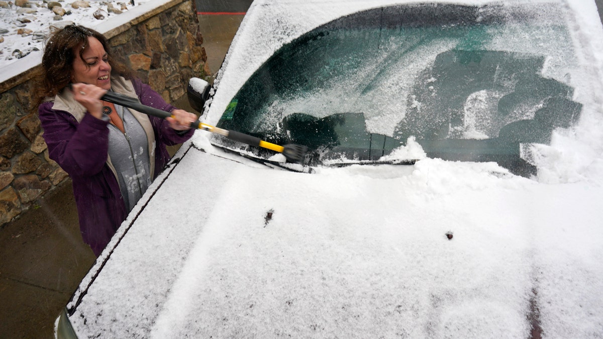Diane Lee cleans the windshield of her sports-utility vehicle as she heads home after a day at her job with the Clear Creek County Sheriff's Department while a storm packing high winds and snow sweeps through the intermountain West Tuesday, Sept. 8, 2020, in Georgetown, Colo.