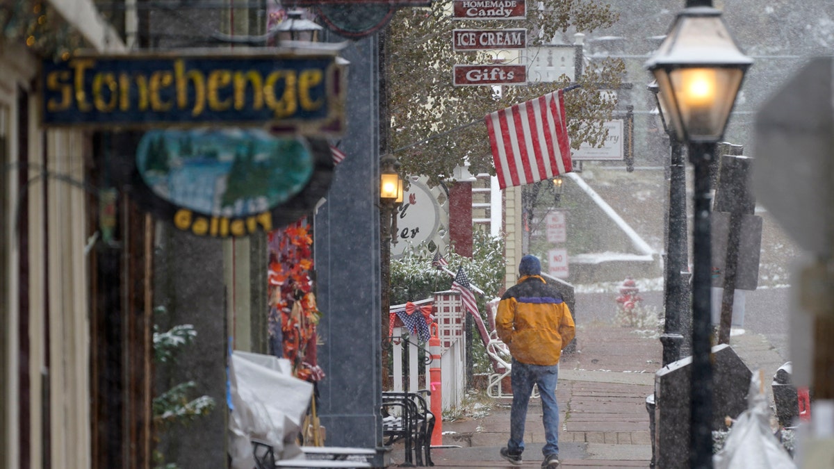 A lone pedestrian moves along the main street as a storm packing high winds and snow sweeps through the intermountain West, Tuesday, Sept. 8, 2020, in Georgetown, Colo.