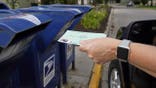 FILE - In this Tuesday, Aug. 18, 2020, file photo, a person drops applications for mail-in-ballots into a mail box in Omaha, Neb. (AP Photo/Nati Harnik, File)