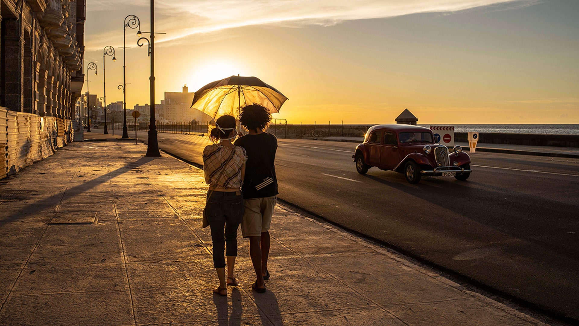 A couple walks along the Malecon at sunset in Havana, Cuba, Aug. 31, 2020. 
