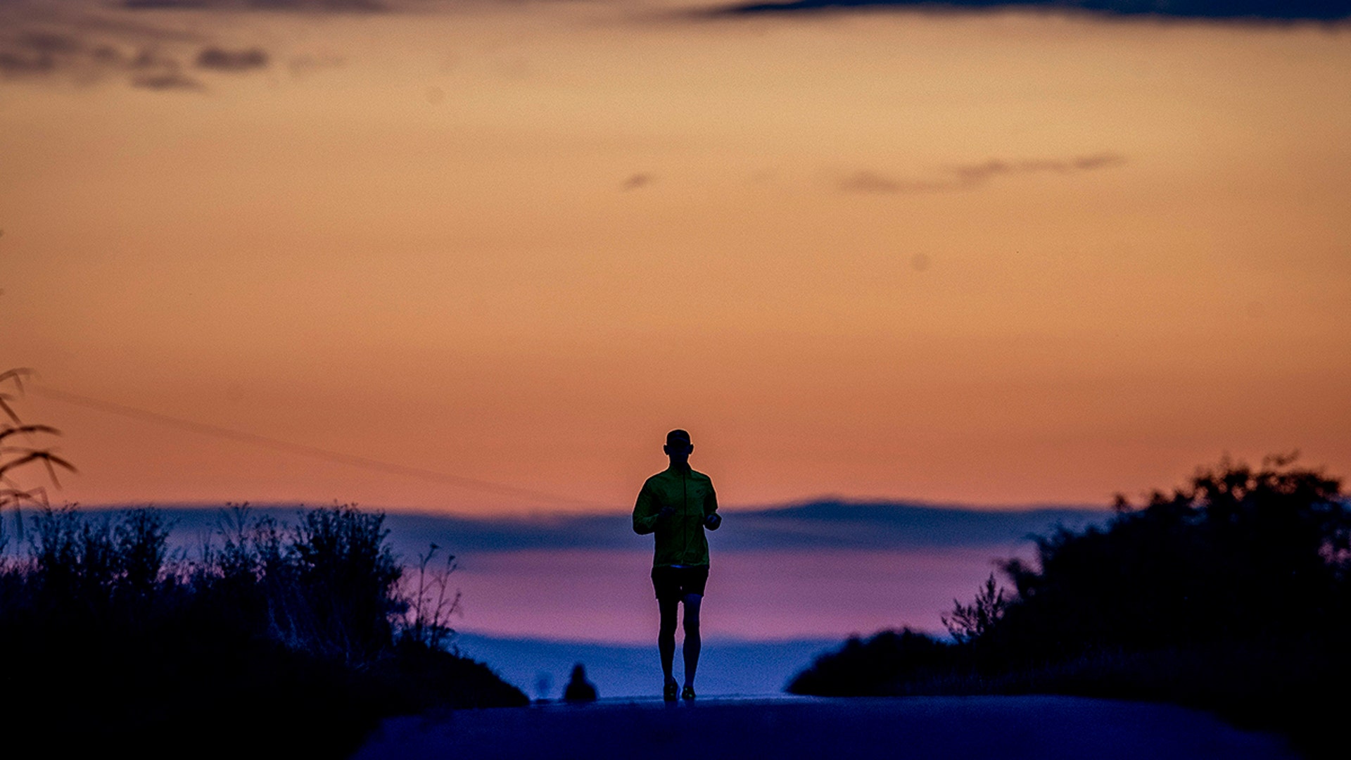 A man runs on a small road before sunrise in Frankfurt, Germany, Sept. 1, 2020.
