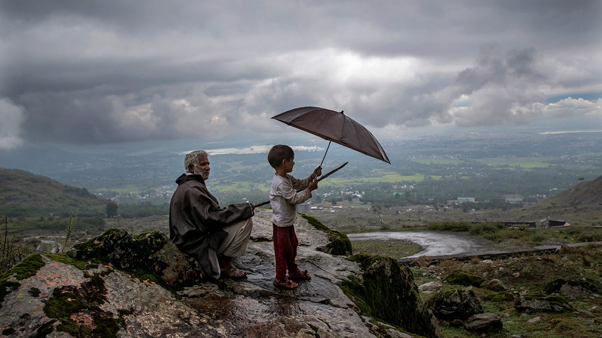 Ali Mohammad a Kashmiri villager with his grandson Burhan Ahmed keeps a watch on their cattle from a hilltop on the outskirts of Srinagar, India, Aug. 31, 2020.