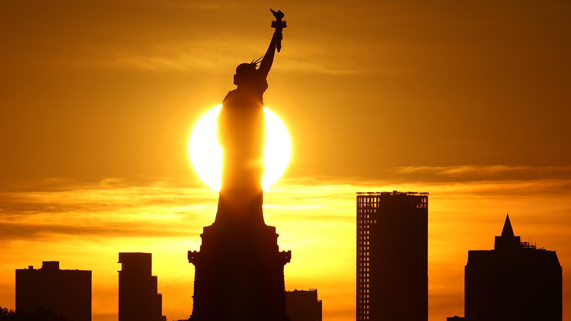 The sun rises behind the Statue of Liberty in New York City, August 30, 2020