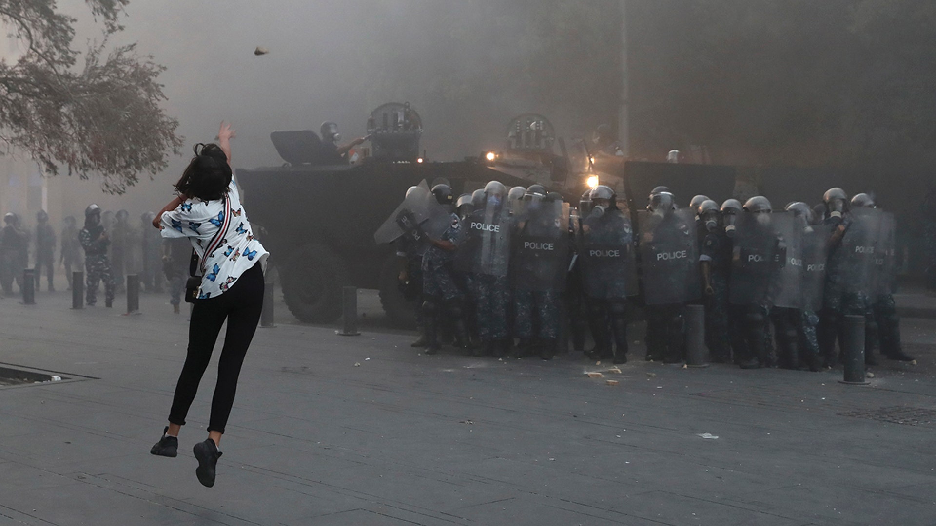An anti-government protester throws a stone toward riot police during a protest near Parliament Square, In Beirut, Lebanon, Sept. 1, 2020. 