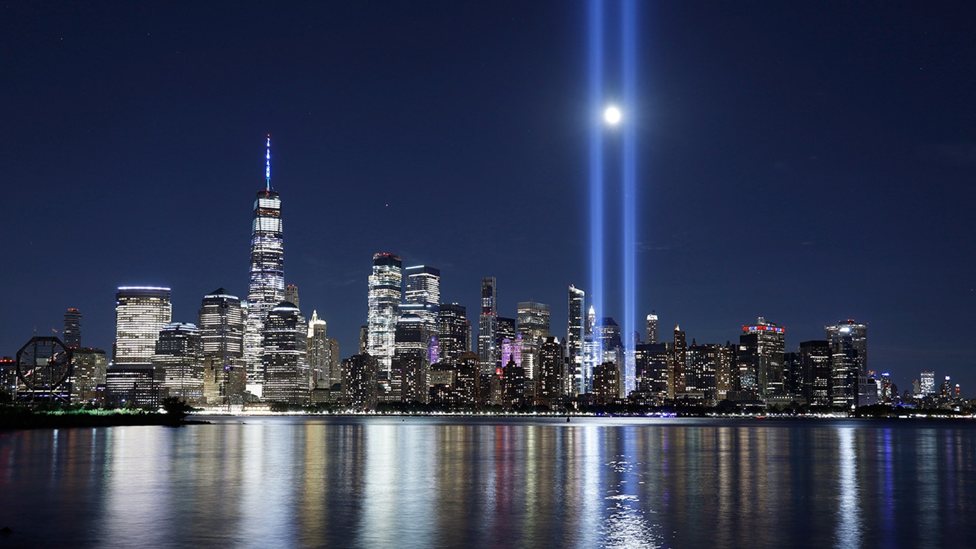 The moon rises between the beams of the Tribute in Light as it is tested over lower Manhattan and One World Trade Center in New York City, Sept. 4, 2020. 