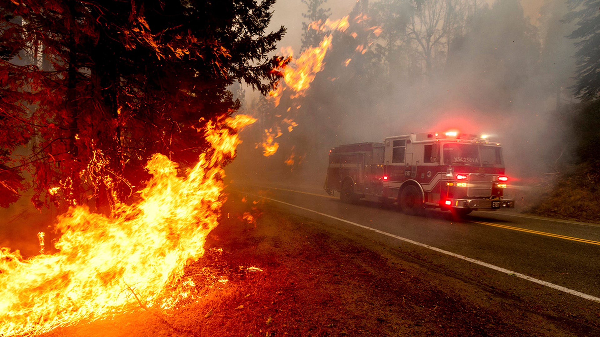 A firetruck drives along state Highway 168 while battling the Creek Fire in the Shaver Lake community of Fresno County, Calif., on Sept. 7, 2020. A weekend wildfire east of Fresno exploded so fast that it trapped hundreds of holiday campers who were airlifted to safety in a dramatic rescue that strained the limits of two California National Guard helicopters. 